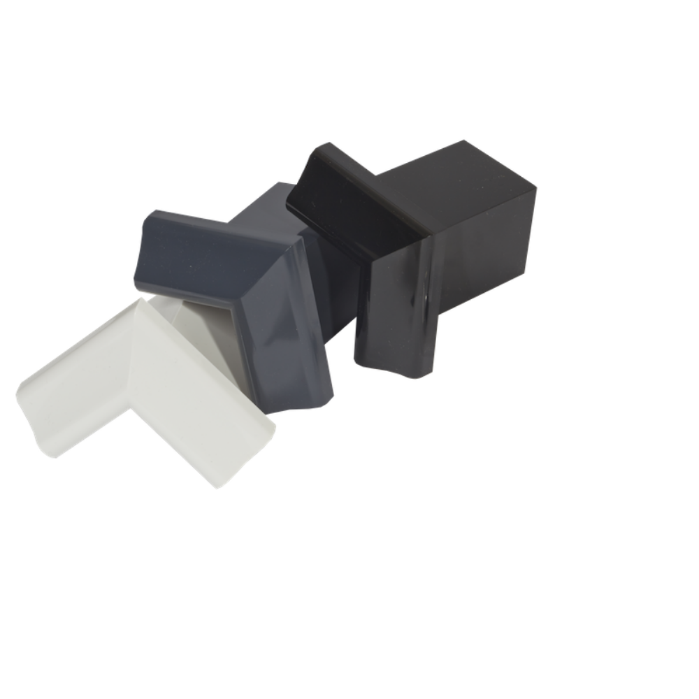 Three edge trim internal corner pieces lying down, first the white, then the anthracite grey, then the black. 